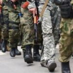 На фото бойцы СВО на Донбассе идут в военном строю с оружием в руках